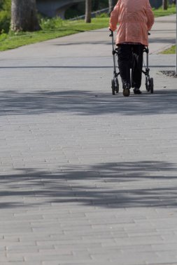 güneşli bir bahar kıdem Bayan rollator Park Güney Almanya ile yürür.