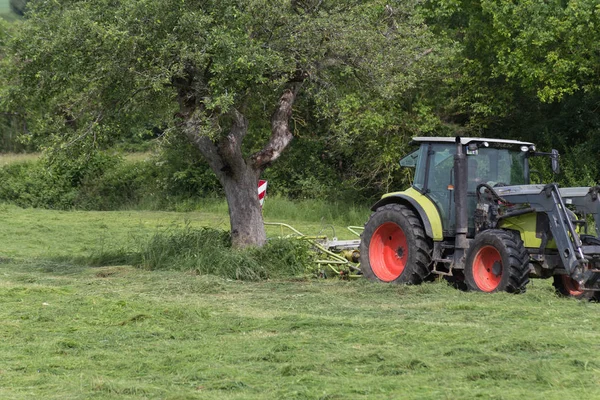 月に南ドイツの非常に晴れた日のトラクターと農家の動物食品の花粉を作るが表示します — ストック写真