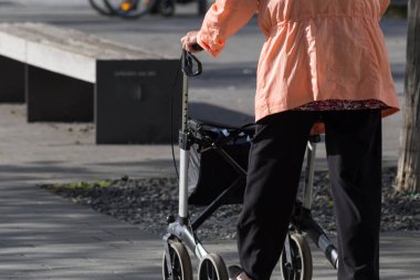 güneşli bir bahar kıdem Bayan rollator Park Güney Almanya ile yürür.