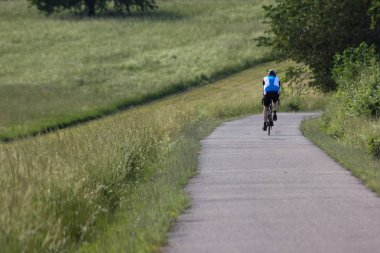 Haziran ayında Güney Almanya çok güneşli bir günde bisikletçi sürüş ve bir yol çalışan jogger görmek