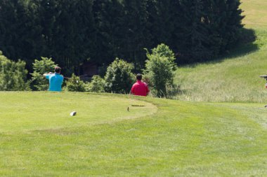 çok güneşli bir Güney Almanya'da golf çim yeşil gördüğünüz ve bayrak ve oyuncular ve kum alanları ve golfplace çevresinde yolu olan mahkeme