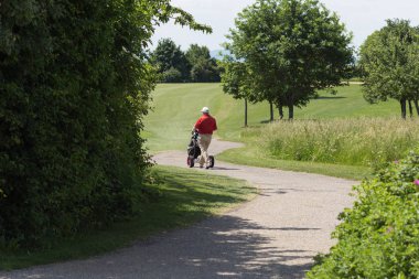 çok güneşli bir Güney Almanya'da golf çim yeşil gördüğünüz ve bayrak ve oyuncular ve kum alanları ve golfplace çevresinde yolu olan mahkeme
