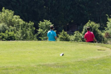 çok güneşli bir Güney Almanya'da golf çim yeşil gördüğünüz ve bayrak ve oyuncular ve kum alanları ve golfplace çevresinde yolu olan mahkeme