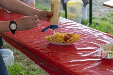 Açık parti üzerinde lezzetli Fransız kızartması sunucu kırmızı ketçap ve mayonez ile birlikte Alman bira bardak kırmızı bir tablo ile servis edilir