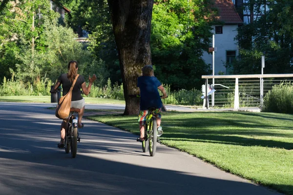 on a evening in june in south germany in center park of a historical city you see people moving through and having a good time in shadow giving park