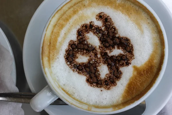 italian cappuccino with german pretzel with chocolate artwork on creme of coffee on metal table top in south german historical city near munich and stuttgart