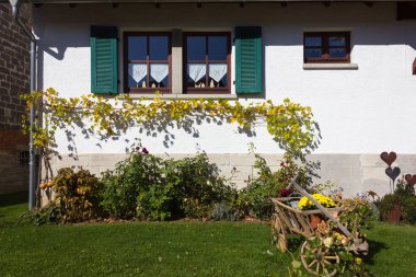 german farmhouse with autumn colors and decoration of garden in fall october bright colorful sunny day