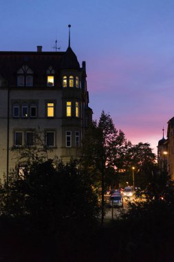 bir Ekim tarihinde akşam binalar, hafifleyen windows ve gökyüzü güney Almanya stuttgart yakınındaki bir şehir gökkuşağı renkleri ile aydınlatılmış sokaklar düşmek