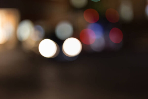 Citylights at night with bokeh effects of traffic passing by and storefronts behind with neon lamps shine through