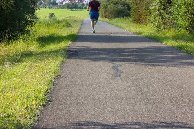 Eylül ayında açık egzersiz çalışan adam yanında yeşil çim ve güneşli hava durumu ile Güney Almanya'da sezon sonbahar