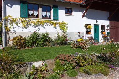 german farmhouse with autumn colors and decoration of garden in fall october bright colorful sunny day