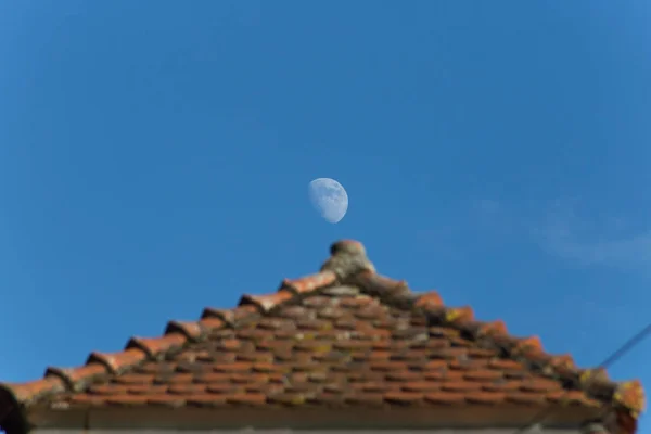 月に南ドイツで非常に日当たりの良い夜に電源ラインと建物と青い空だけでなく部分的に月を見ることができるツールを表示します — ストック写真