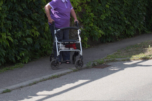 Old woman using rollator in village of southern Germany.