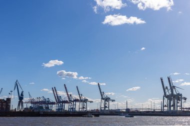 Hamburg konteyner terminal bağlantı noktası Dock teçhizatları ve gemilerde bir sprintime Mart öğleden sonra güneş mavi gökyüzü ve bulutlar ile parlak