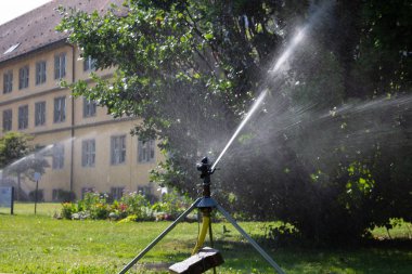 İlkbahar sabah spinkle ekipman tarihsel bir park Güney Almanya şehir Stuttgart-yeşil çim üzerinde