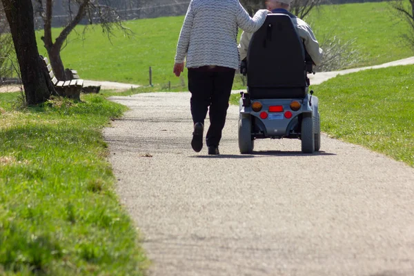 在德国南部的东部春天 在蓝天阳光明媚的假期上 带着摩托里文轮椅的高级夫妇 — 图库照片