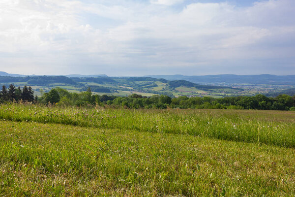 Landscape mountainous springtime with sunbeams green grass forests blue sky in south germany