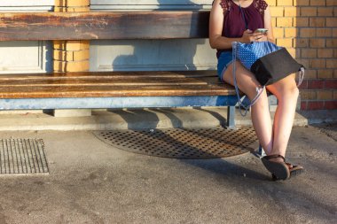 tuğla Bavyera Güney Almanya'da sıcak yaz günü duvar önce trainstation, bankta oturan genç bayan