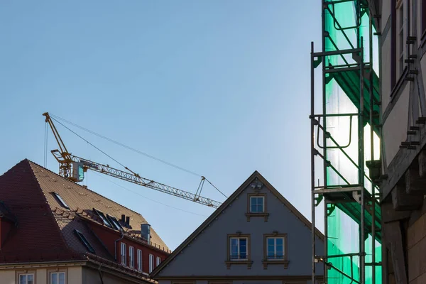 scaffolding with green cover on blue sky afternoon in historical city schwaebisch gmuend in south germany