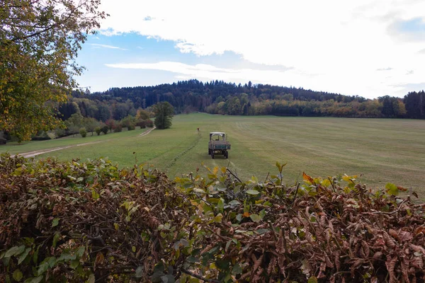 拖拉机和老高级农民挖草坪在10月秋天月在德国南部农村 — 图库照片