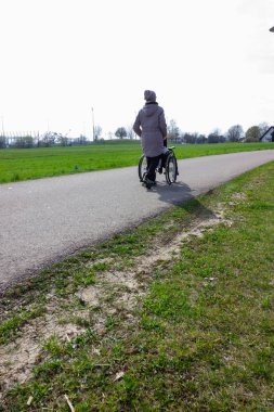 güney Almanya'da ilkbaharda bisiklet yolunda tekerlekli sandalye iten kıdemli bayan
