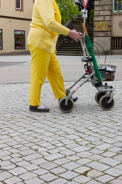 Старший леді в жовтій сукні з роллятор — стокове фото
