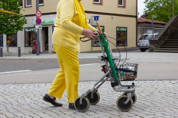 Senior lady in yellow dress with rollator — Stock Photo, Image