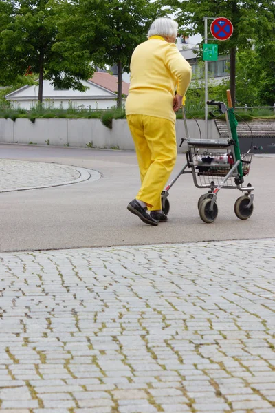 Senior lady in yellow dress with rollator — Stock Photo, Image