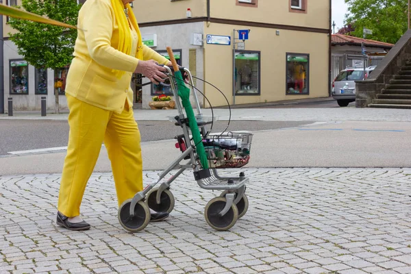 Senior lady in yellow dress with rollator — Stock Photo, Image
