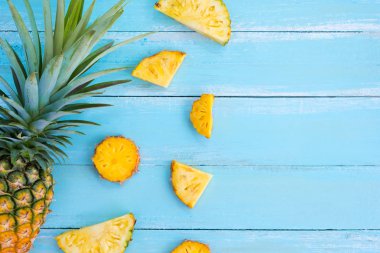 Tropikal ananas dilimleri ahşap üzerine mavi renk plank. çerçeve düzeni yaz tatil arka plan kavramı. üstten görünüm, bilmece