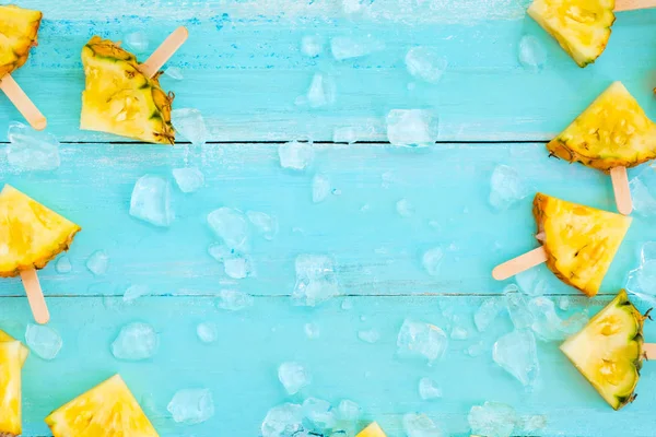 Ahşap tahta mavi renk üzerinde buzlu buzlu çubuk sopa ananas dilimleri. yaz meyve backgrond kavramı, üstten görünüm, kopya alanı