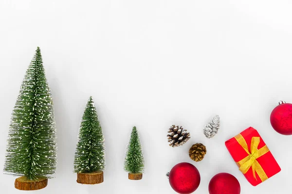 Noel ve yeni yıl arka plan. Noel ağacı, kırmızı topları, çam kozalakları ve hediye kutusu beyaz kağıt üzerinde. Yaratıcı düz yatıyordu, en iyi görünümü
