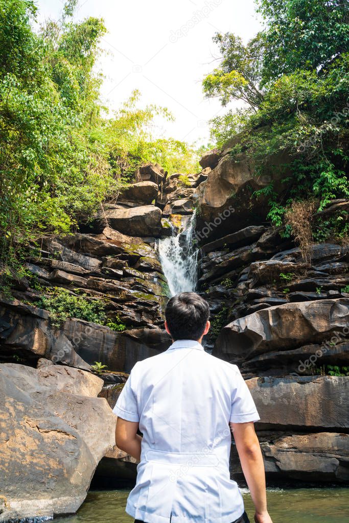 Man with white shirt stand in front of unseen waterfall