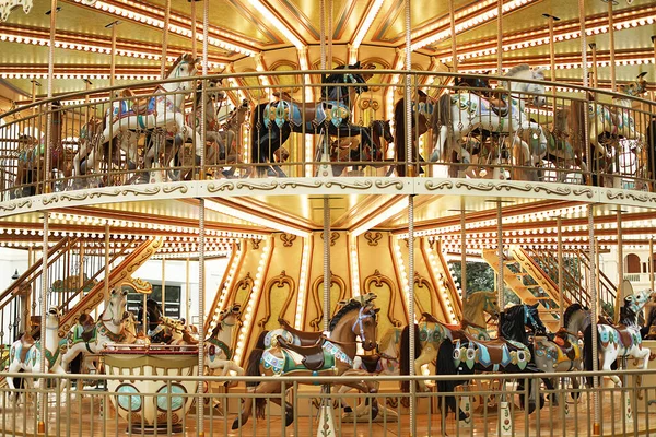 Horses on a traditional childrens carousel. Wooden horses spin around the post. Joy for children.