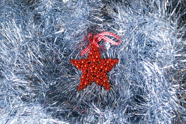 Christmas decorative toy red star lying on a silver glittering background. Idea for New Year wallpapers and cards