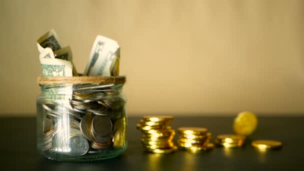 Saving money coin in jar. Symbol of investing, keeping money concept. Collecting cash banknotes in glass tin as moneybox — Stock Video