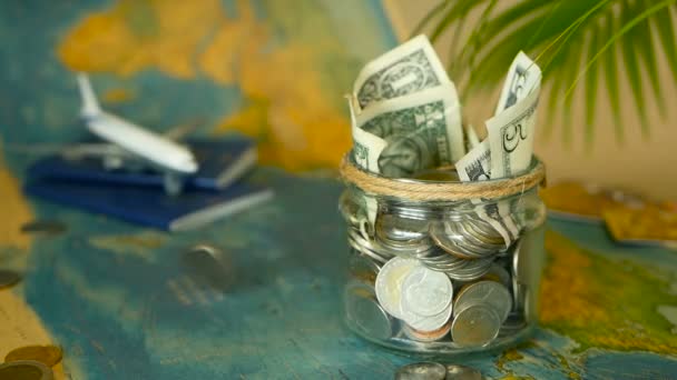 Travel budget concept. Money saved for vacation in glass jar on world map background — Stock Video