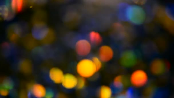 Defocused shimmering multicolored glitter confetti, black background. Holiday abstract festive bokeh light spots. — Stock Video