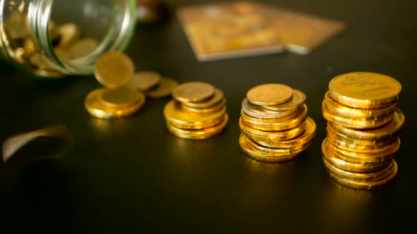 お金の概念を維持投資のシンボルです。黒いテーブルの上の金のコインの列を増やすクローズ アップのある静物 — ストック動画