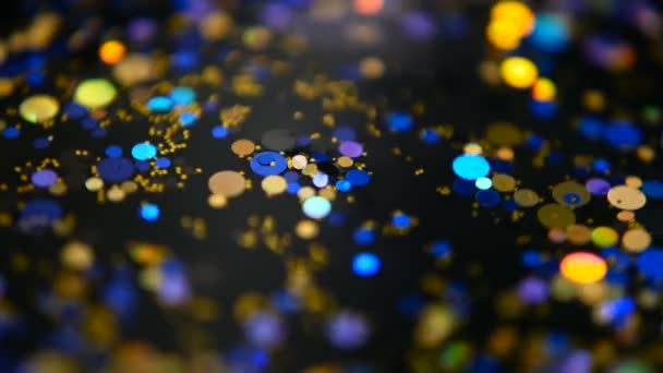 Intreepupil glinsterende veelkleurige glitter confetti, zwarte achtergrond. Vakantie abstracte feestelijke bokeh licht vlekken. — Stockvideo