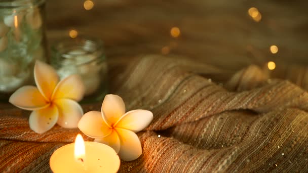 Frasco de vidro cheio de conchas, corais, itens marinhos com luzes de vela, flores plumeria frangipani para decoração — Vídeo de Stock