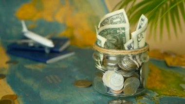 Seyahat bütçe kavramı. Tasarruf tatil için cam kavanozun içinde dünya harita arka plan üzerinde