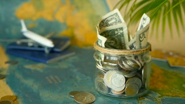 Cestovní rozpočet koncept. Ušetřené peníze na dovolenou do sklenic na pozadí mapy světa — Stock video