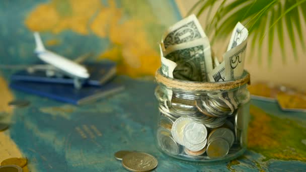 Travel budget concept. Money saved for vacation in glass jar on world map background — Stock Video