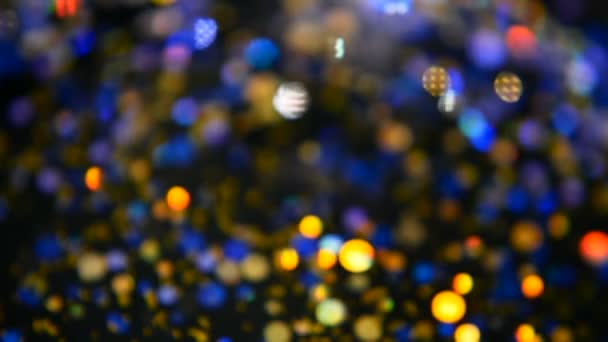 Defokussiert schimmerndes buntes Glitzerkonfetti, schwarzer Hintergrund. Urlaub abstrakte festliche Bokeh Lichtpunkte. — Stockvideo