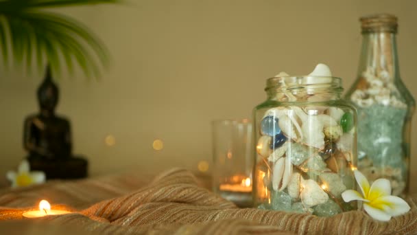 Deniz kabuklarını, mercanlar, deniz öğeleri mum ışıklı plumeria çiçekler, Buda dekorasyonu için oturma ile dolu cam şişe — Stok video