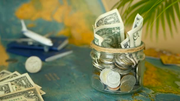 Travel budget concept. Money saved for vacation in glass jar on world map background — Stock Video