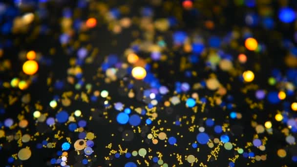 Desfocado cintilante multicolorido glitter confetti, fundo preto. Férias abstrato festivo bokeh pontos de luz . — Vídeo de Stock
