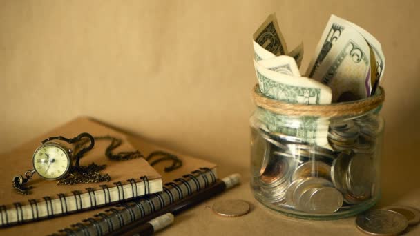 유리 페니 항아리와 책 동전과 지폐를 가득합니다. 수업료 또는 교육 금융 개념. 장학금 돈. — 비디오