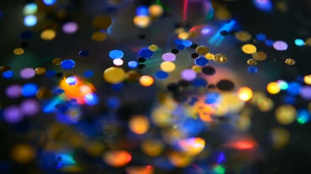 Defokussiert schimmerndes buntes Glitzerkonfetti, schwarzer Hintergrund. Urlaub abstrakte festliche Bokeh Lichtpunkte. — Stockvideo